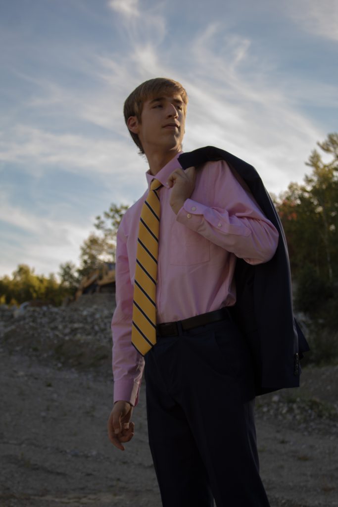 my brother in a pink shirt, yellow and blue tie, blue pants, with a blue suit jacket over his shoulder